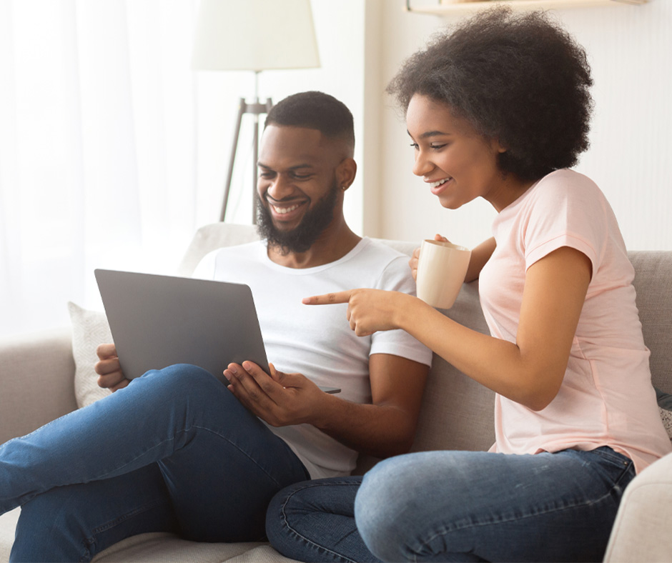 Young adults looking at laptop computer. Why join a credit union? 7 benefits that make the difference.