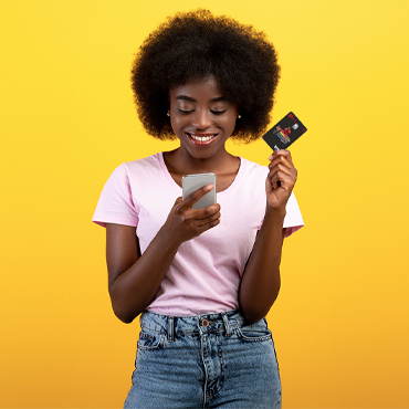 Woman looking at phone while holding a credit card